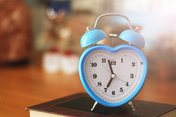 Blue alarm clock in the form of a heart in the interior © sabdiz