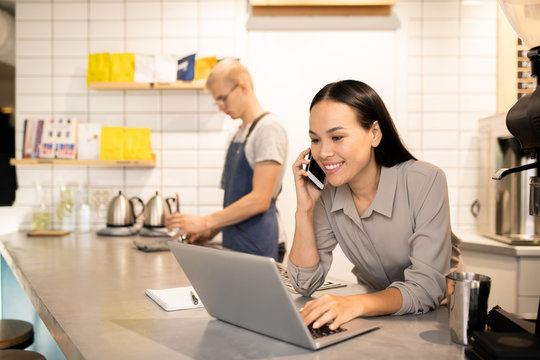 Young manager of restaurant consulting clients on the phone in front of laptop - Powered by Adobe