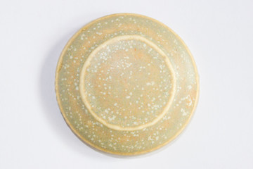 round clay sample covered with beige matte glaze.