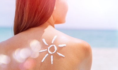 Beautiful Woman with Sunscreen Solar Cream over ocean background. Sun Tanning. Skin care and...