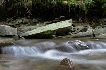 Small waterfall in the mountain forest with stones, long exposure