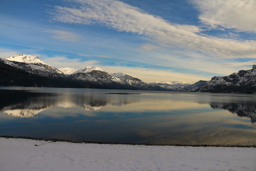 Obraz na płótnie Canvas vista de gran angular de un lago con montañas, nieve y nubes