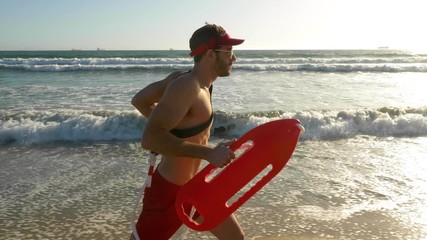 Male lifeguard running along the beach