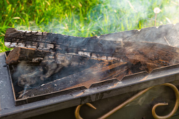 Smoldering firewood and embers in a steel barbecue