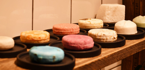 Obraz na płótnie Canvas An image of nine various decorative round soap bars of different colors and one bar of white rectangular soap made of natural ingredients