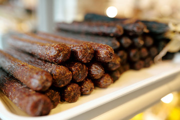 Stack of tasty and spicy fresh sausages in display with meat products