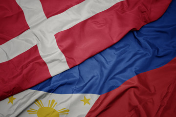 waving colorful flag of philippines and national flag of denmark.