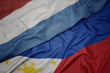 waving colorful flag of philippines and national flag of luxembourg.