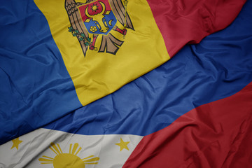 waving colorful flag of philippines and national flag of moldova.