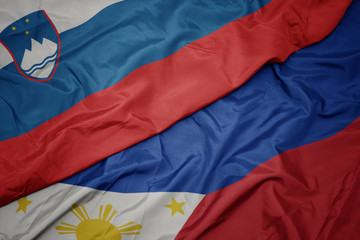 waving colorful flag of philippines and national flag of slovenia.
