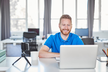 Young Caucasian employee sitting in office and typing on laptop. Start up business concept.