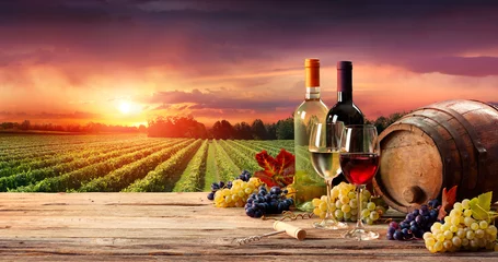 Foto auf Acrylglas Fassweingläser und Flasche im Weinberg bei Sonnenuntergang © Romolo Tavani