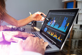 People Analyzing Graph On Laptop