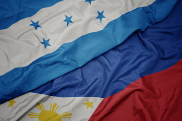waving colorful flag of philippines and national flag of honduras.