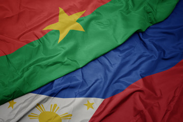 waving colorful flag of philippines and national flag of burkina faso.