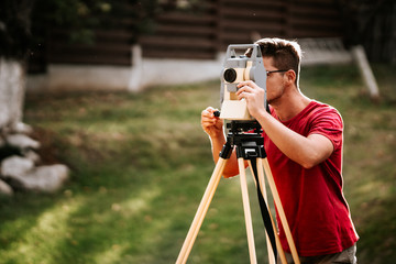 portrait of smiling surveyor working with total station with coordinates, cartography industry...