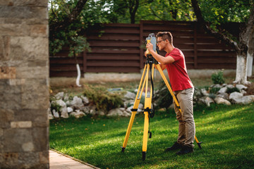 portrait of professional surveyor working with total station theodolite on landscaping project