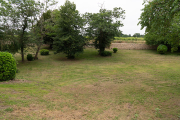 Green garden lawn and trees surrounded by stone wall