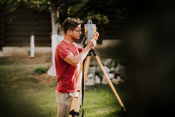 Portrait of surveyor engineer working with total station theodolite and gps system on construction...
