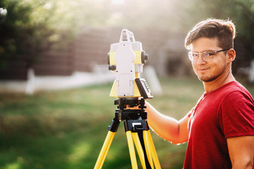 portrait of handsome surveyor working with total station with coordinates, cartography industry...