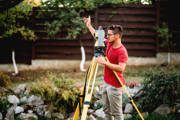 survey engineer in garden elevation construction site using and working with theodolite