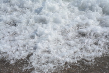 Sea foam hisses in the sand during a storm