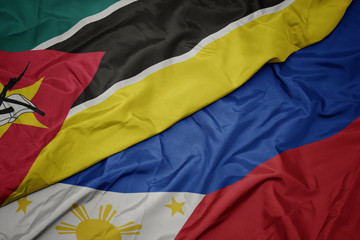 waving colorful flag of philippines and national flag of mozambique.
