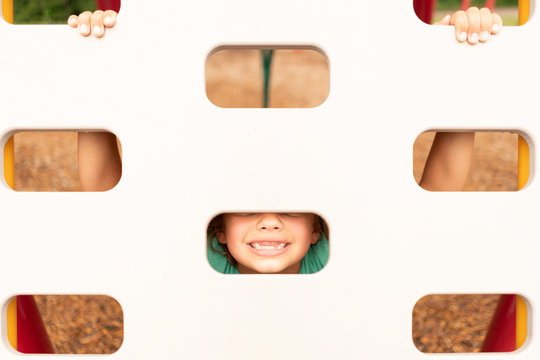 Close up view of girl smiling through small opening in wall