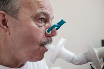 Senior hispanic man man testing breathing function by spirometry. Diagnosis of respiratory function...