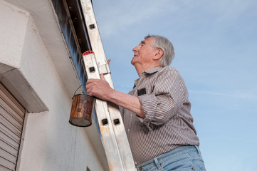 Senior climbing up a dangerous ladder 