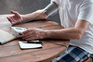 View on man using a home blood pressure machine to check his health. No face