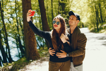 A stylish and bright love couple walks in the sunny forest