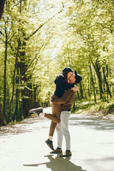 A stylish and bright love couple walks in the sunny forest