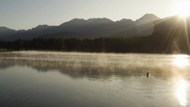 Man Kayaking During Foggy Sunrise