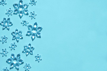 Clear glass decorative snowflakes in bright sunlight on trendy light blue background. Minimal christmas concept. Copy space for text. Flat lay style. Open composition.