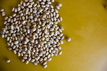 Dry and uncooked brown beans with a warm and yellow background