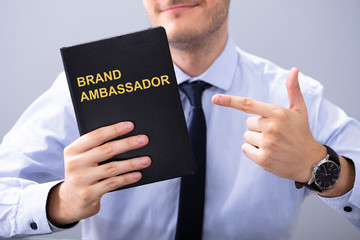 Man Holding Book With Brand Ambassador Text