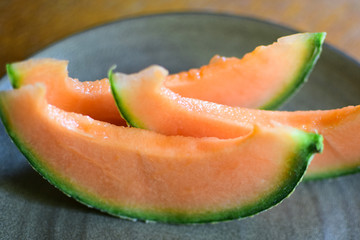 Juicy slices of ripe orange melon on a ceramic plate.
