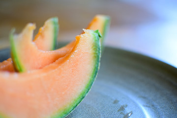 Juicy slices of ripe orange melon on a ceramic plate.