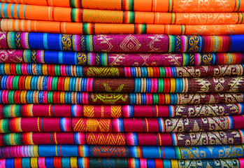 A pile of colorful traditional textiles in the Andes mountain range sunday market of Otavalo, north...