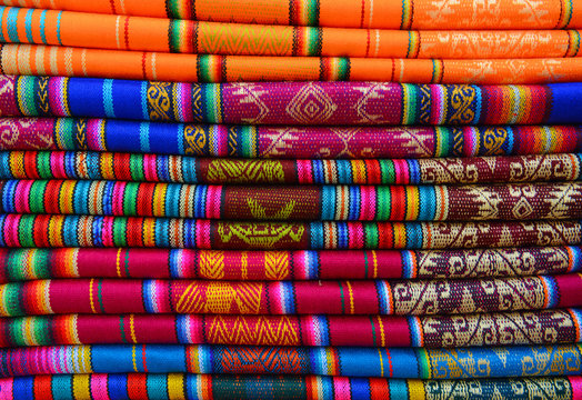 A pile of colorful traditional textiles in the Andes mountain range sunday market of Otavalo, north of Quito, Ecuador.