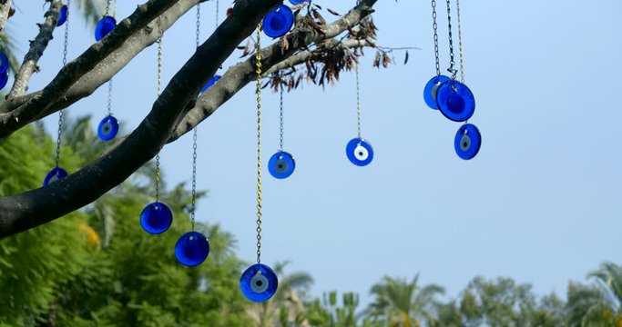 arabic nazar amulets protect against the evil eye are hanging on chains on branches of tree in garden