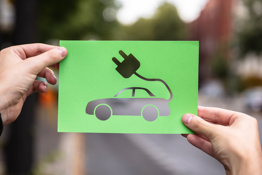 Hands Holding Paper With Cutout Electric Car