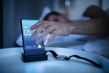 Man Waking Up With Alarm On Mobile Phone