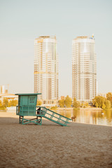Closed lifeguard station on an empty beach in autumn against a modern urbanistic background