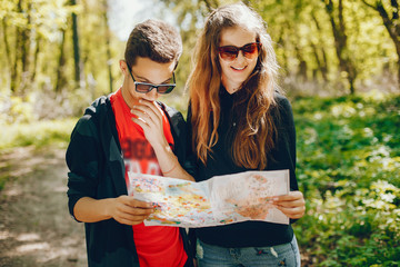Couple walking in a autumn forest. Tourists use the map. Boy and girl have fun in a park