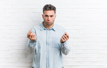 Young handsome man against a bricks wall showing that she has no money.