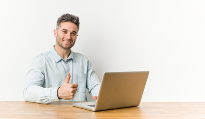 Young handsome man working with his laptop smiling and raising thumb up