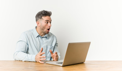 Young handsome man working with his laptop being shocked because of something she has seen.