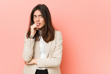 Young brunette business woman against a pink background relaxed thinking about something looking at...